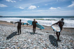 three paddleboarders on the beach