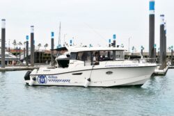 Leisure motorboat cruising past pontoons in a marina.