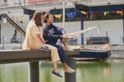 A man and woman sitting on a wooden dock