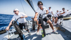 crew winching on the deck of a racing sailing boat