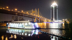 Ocean Cleanup boat collecting plastic on river at night
