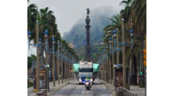 Wrapped hull of INEOS yacht on lorry with police motorbike escort into Barcelona