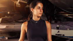 Lone sailor stares into distance while standing in front of boats